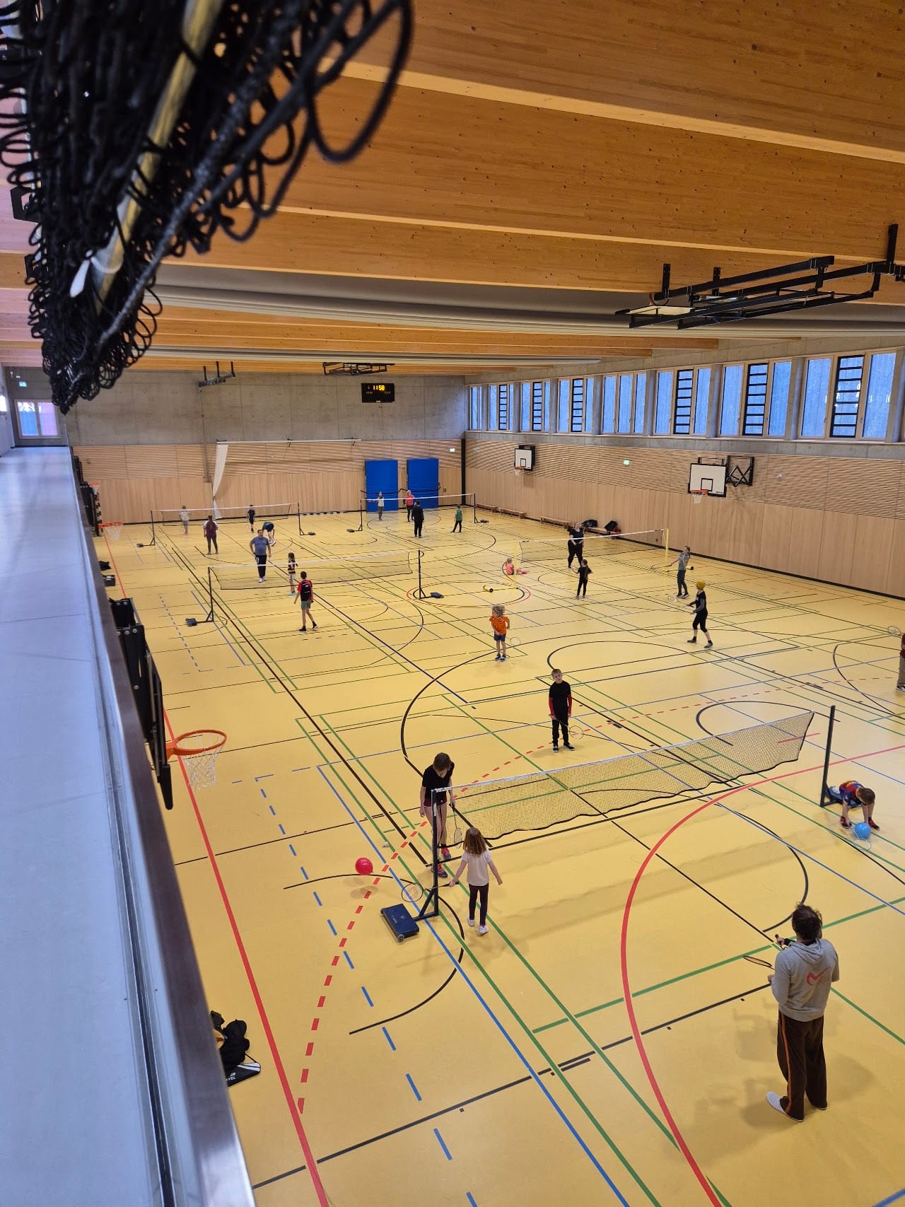 Blick in eine volle Trainingshalle des Köpenicker Badminton Club: Kinder und Erwachsene spielen nebeneinander auf mehreren Feldern
