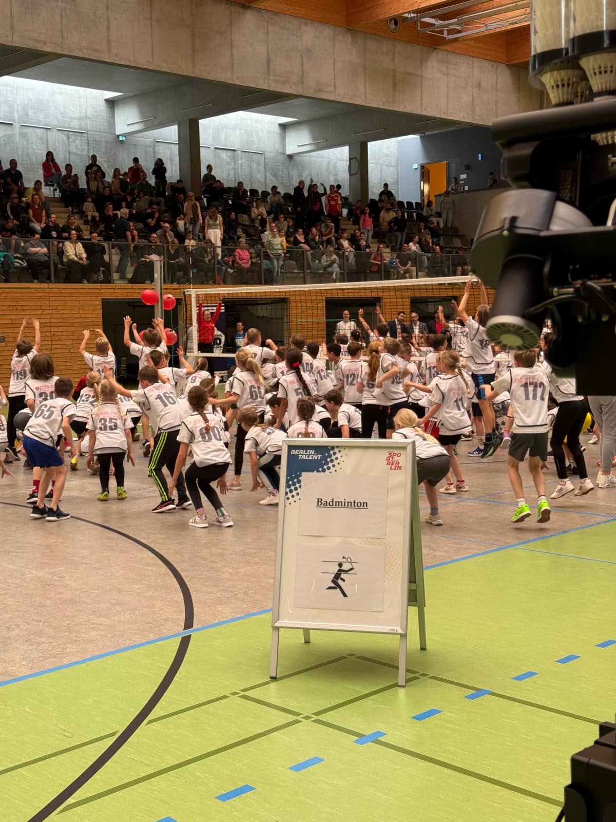 Kinder beim gemeinsamen Aufwärmen vor vollen Rängen bei einer Sportveranstaltung