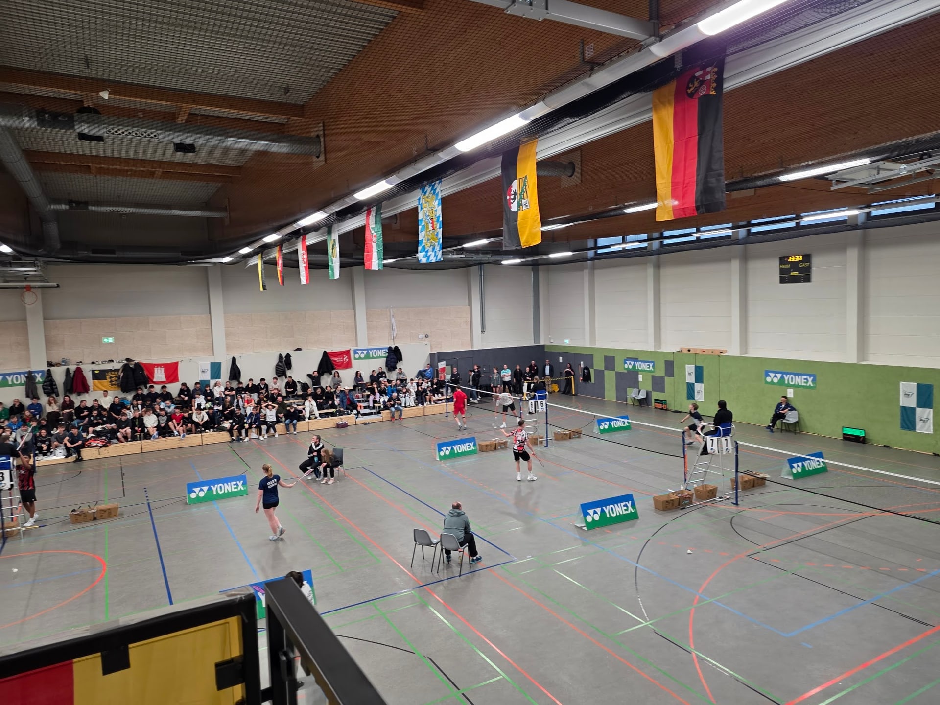 Blick über mehrere Spielfelder und volle Ränge bei einem Badminton-Turnier mit Landesflaggen