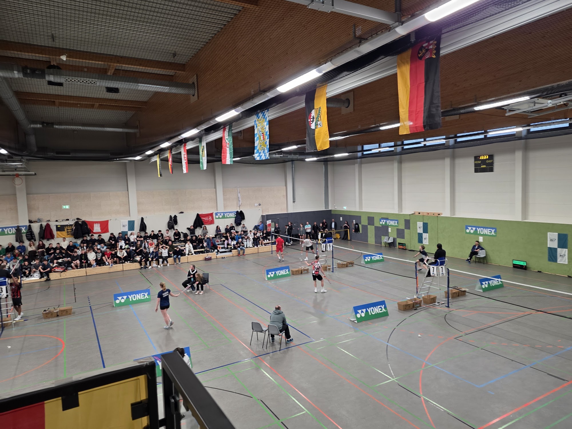 Blick über mehrere Spielfelder und volle Ränge bei einem Badminton-Turnier mit Landesflaggen